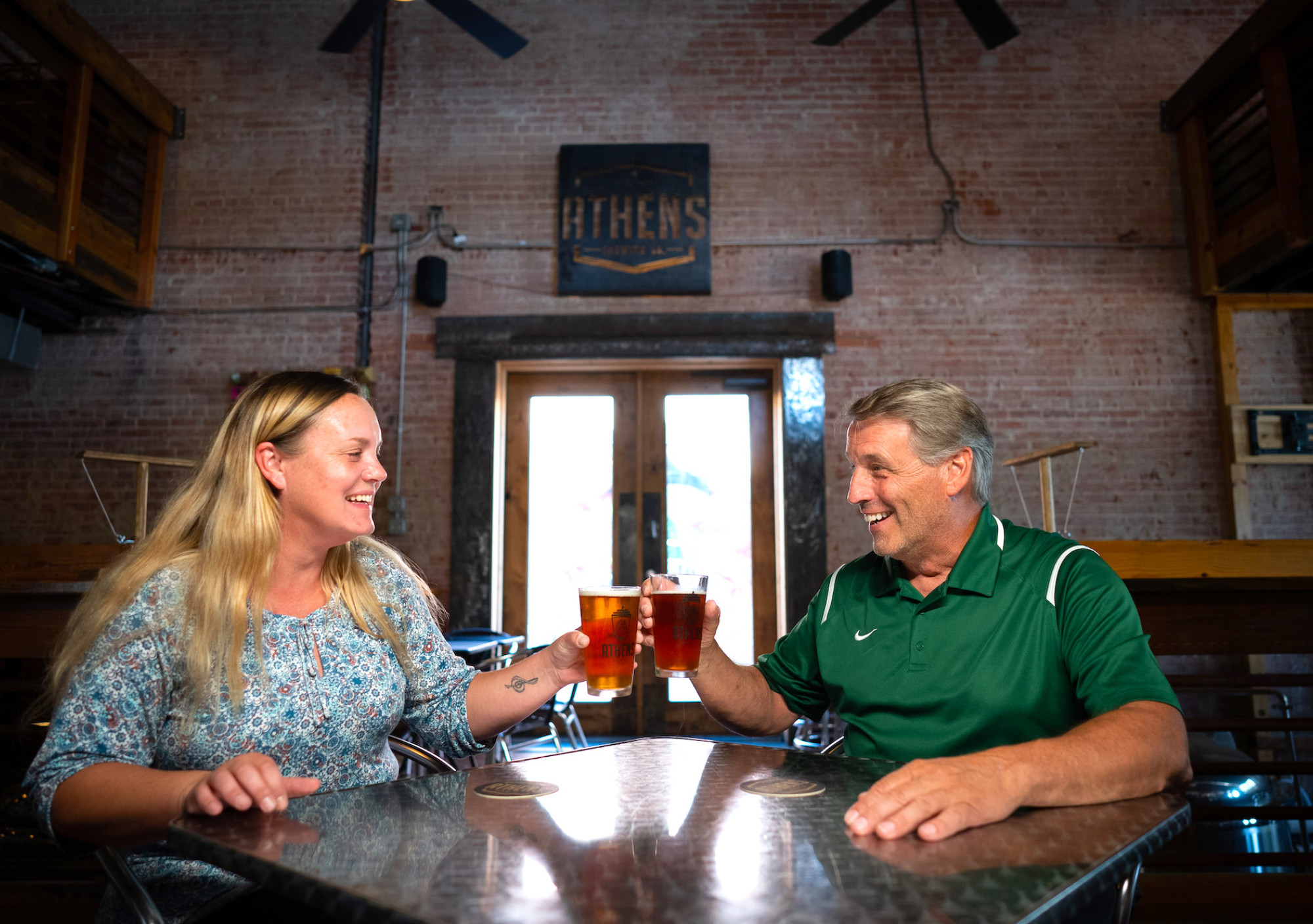 Two people sitting in Athens Brewery drinking together